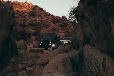 Car on road by rock formation against sky