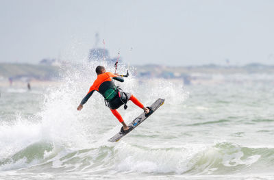 Low angle view of man kiteboarding in sea against sky