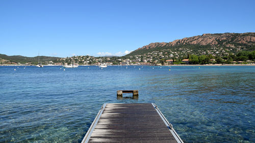 Pier over sea against clear blue sky