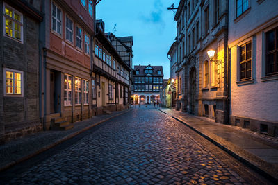 Street amidst buildings in city at dusk