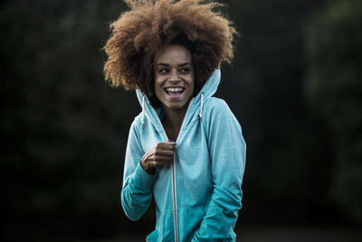 Cheerful woman wearing hooded shirt in park