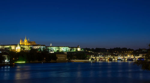 Illuminated buildings against blue sky at night