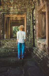 Rear view of mid adult woman standing outside ankor wat temple