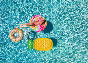 High angle view of woman floating on inflatable lollipop in swimming pool