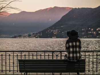 Rear view of woman standing by railing against lake