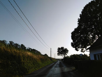 Empty road amidst trees against clear sky