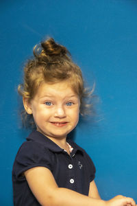 Portrait of smiling girl standing against blue background