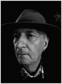 Close-up portrait of man wearing hat against black background