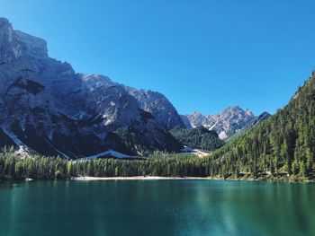 Scenic view of lake and mountains against clear blue sky