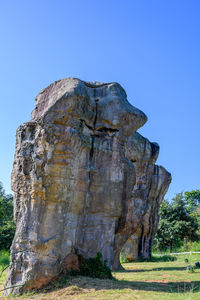 Low angle view of rock formation on field against clear sky
