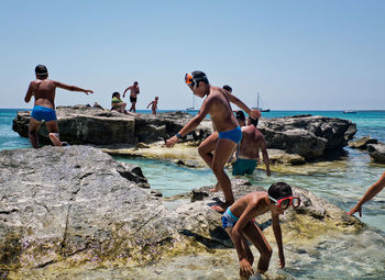 Friends enjoying on beach against clear sky