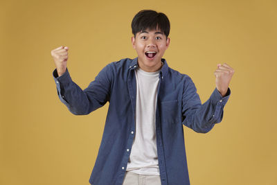 Portrait of smiling man standing against yellow background