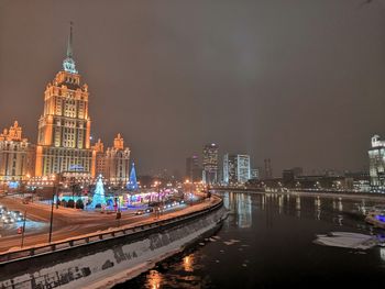 Illuminated buildings by river at night