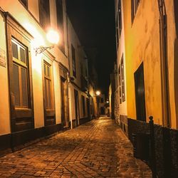 Illuminated street amidst buildings at night