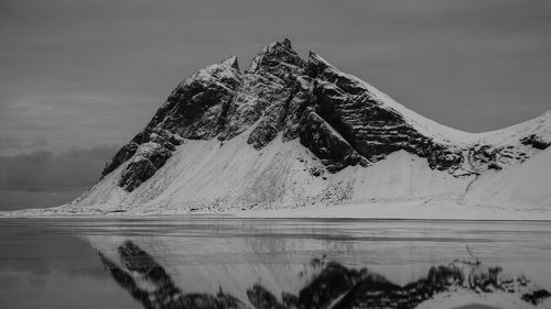 Scenic view of lake by snowcapped mountains against sky