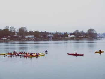 People boating on river against sky