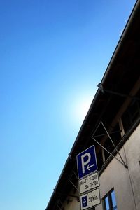 Low angle view of road sign against clear blue sky