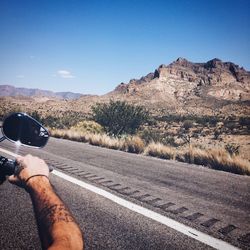 Person riding bike on road against clear sky