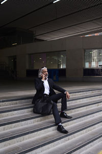 Stylish senior businessman on the phone sitting on stairs outdoors