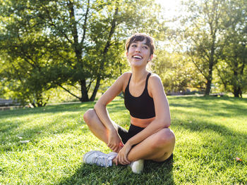 Happy young athlete sitting on grass in park