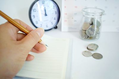Cropped image of hand holding clock at table