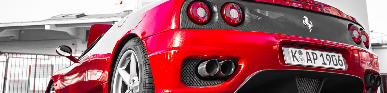 CLOSE-UP OF RED VINTAGE CAR ON ROAD