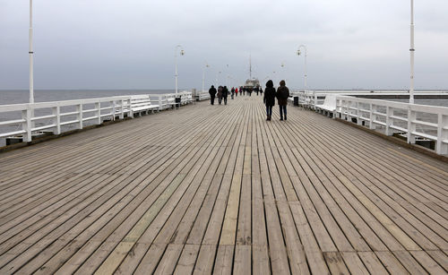 People on promenade by sea against sky