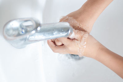 Close-up of person washing hands under faucet