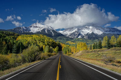 Road to mountain in autumn with aspen yellow leafs