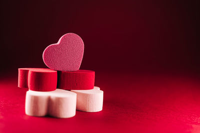 Close-up of heart shape on table against red background