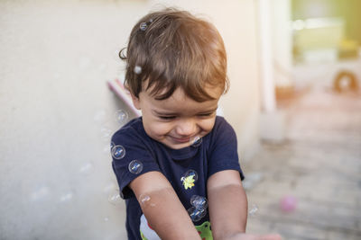 Child with blue t-shirt playing with soap bubbles