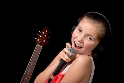 Portrait of girl singing against black background