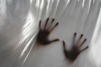 Hands shades behind a white sheet of anonymous person. concept about mental health and illness.