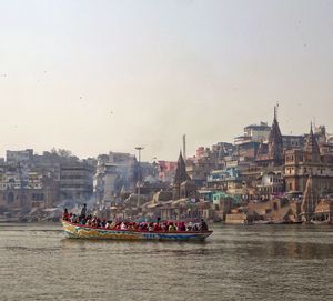 People sailing in river against buildings 