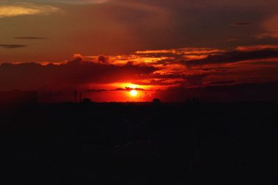 Silhouette landscape against dramatic sky during sunset