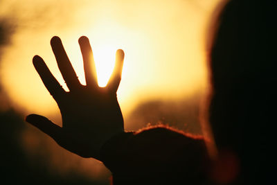 Silhouette hand against sky during sunset