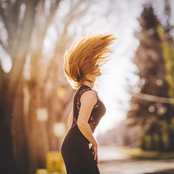 Side view of woman with tousled hair standing at park