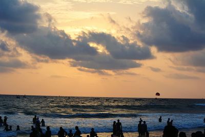 People on beach against sky during sunset