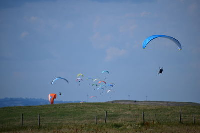 People flying kite on field against sky