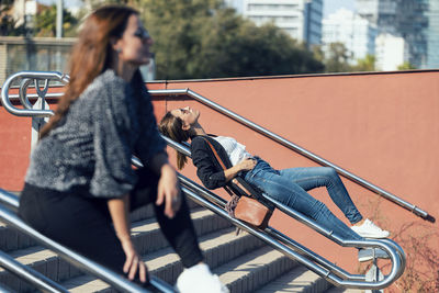 Women relaxing on railing of staircase in city