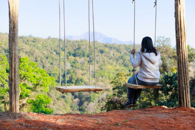 Rear view of woman sitting on swing