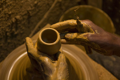 High angle view of cropped hand making pot on pottery wheel