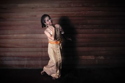Full length of girl in traditional clothing dancing against wall