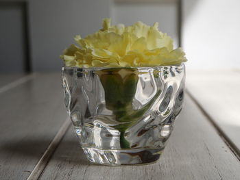 Close-up of yellow flower in glass on table