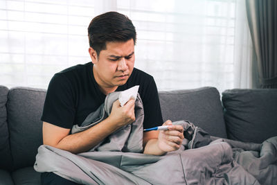 Senior man using phone while sitting on sofa at home