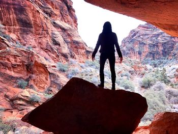 Rear view of man standing on rock formation by mountains at national park