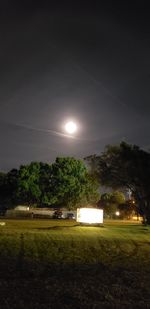 Illuminated street light on field against sky at night