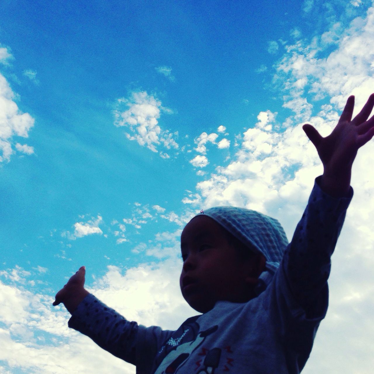 lifestyles, leisure activity, sky, low angle view, cloud - sky, blue, holding, men, headshot, day, cloud, young men, outdoors, casual clothing, standing, person, warm clothing