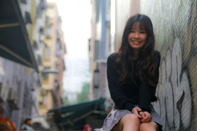 Portrait of smiling young woman sitting outdoors