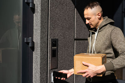 Happy man ringing intercom with camera in entryway.